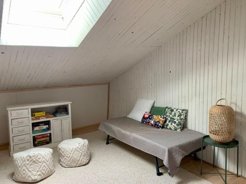 Cette chambre mansardée comprend un lit, une armoire et un tabouret. dans l'établissement Maison Okaina, Sauna, Au centre-ville de Macon, à Mâcon