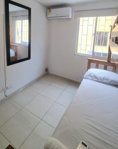 Habitación blanca con cama y espejo en Cómodo Apto piso 3 en Cartagena de Indias