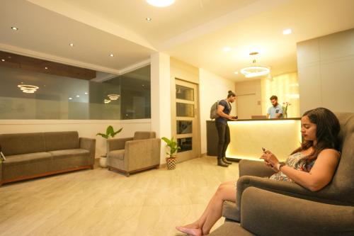 a woman sitting on a couch in a waiting room at Coastal Pearl Hotel Margao Railway Station in Madgaon