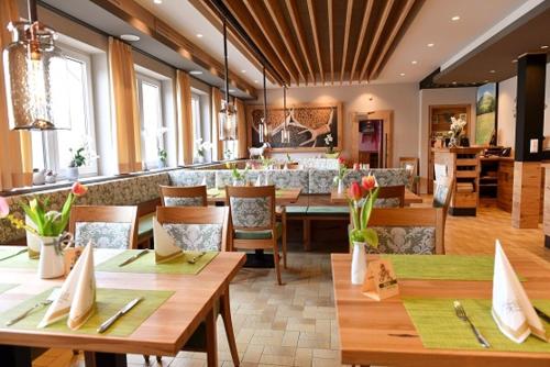Un restaurante con mesas y sillas de madera y un bar. en Köhlers Krone, en Ehingen