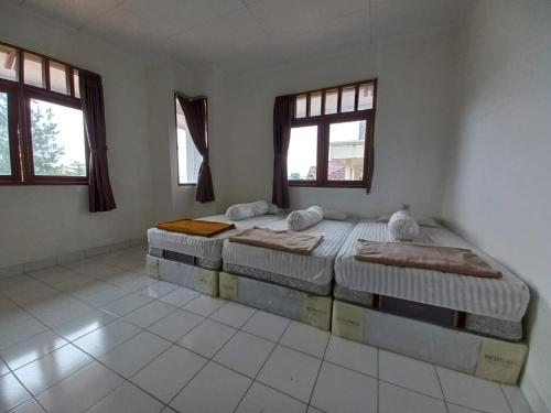 2 Betten in einem Zimmer mit 2 Fenstern in der Unterkunft Villa Cimacan BC 105 in Cipanas