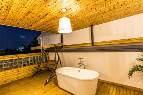 a bathroom with a tub and a chair and a window at Moon Flower Hotel in Guilin