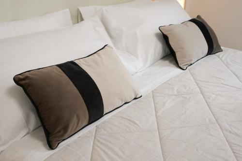 a white bed with black and white pillows on it at Luxury Rooms Paoli 19 in Cagliari