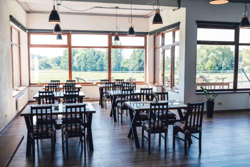a restaurant with tables and chairs and large windows at Penzion Kamence in Liptovský Mikuláš