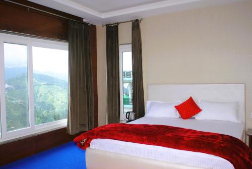 Un dormitorio con una cama con almohadas rojas y una ventana en PinnacleHouse kanatal Uttarakhand, en Kanatal