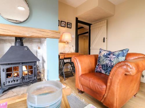 a living room with a leather couch and a fireplace at Bluebell Cottage in Rugeley