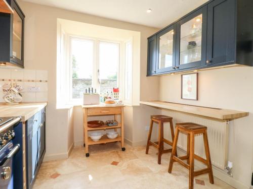 a kitchen with blue cabinets and two stools in it at Bluebell Cottage in Rugeley