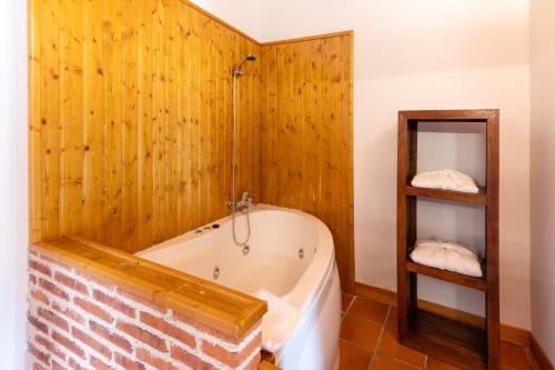 baño con bañera y pared de madera en Hospedería el arco, en Villavieja del Lozoya