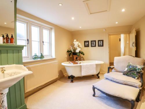 a bathroom with a tub and a chair and a sink at Bluebell Cottage in Rugeley