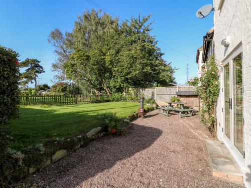 a patio with a picnic table and a yard at Bluebell Cottage in Rugeley