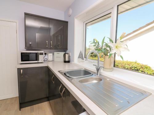 a kitchen with a sink and a microwave and a window at Thornberry in Salcombe