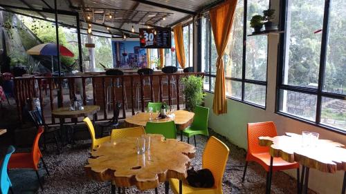 ein Restaurant mit Tischen und Stühlen in einem Zimmer mit Fenstern in der Unterkunft Los Ocobos Libano Tolima - Suite, Hostal y Restaurante in Líbano