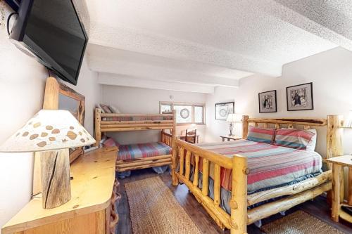 a bedroom with two bunk beds and a flat screen tv at Summit House East 113 in Copper Mountain