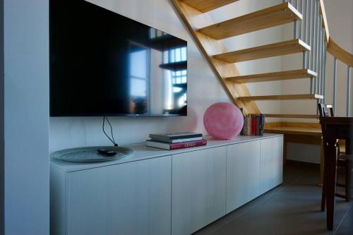 uma sala de estar com uma televisão e uma escada em Trevisan Loft: Slow Food, Langhe, and Comfort em Bra