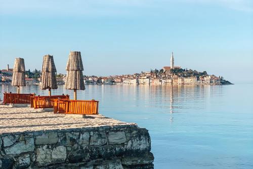 a group of chairs and umbrellas on a pier with the water at Porton Nature Hideouts in Rovinj