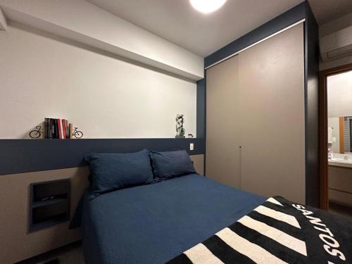 a bedroom with a blue bed with a wall at Flat vista mar em Santos in Santos