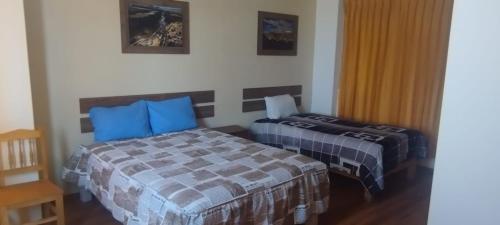 a bedroom with two beds with blue pillows at Hostal Los Andes - Espinar in Espinar