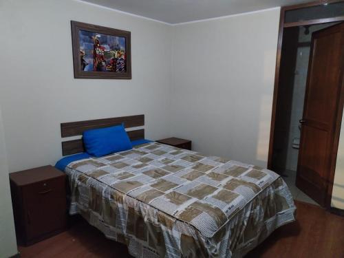 a bedroom with a bed and a picture on the wall at Hostal Los Andes - Espinar in Espinar