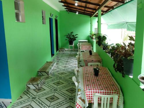 Habitación con paredes verdes, mesas y plantas. en Pousada Do Pedrão en Praia de Japariz 