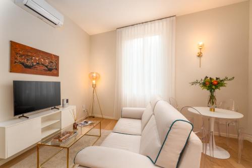 een woonkamer met een witte bank en een televisie bij Residenza del Principe - DB Apartment in Florence