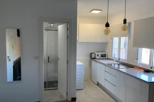eine weiße Küche mit einer Spüle und einer Mikrowelle in der Unterkunft Gelish in Sugdidi