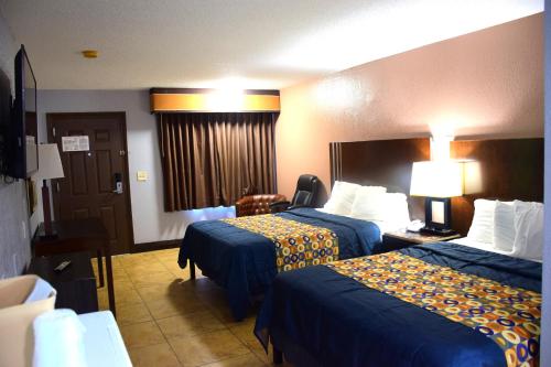 a hotel room with two beds with blue sheets at Flamingo Motel in Okeechobee