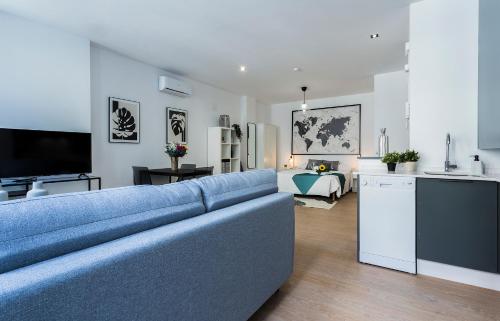 a living room with a blue couch and a kitchen at Rianal Céntrico Moderno in Jerez de la Frontera