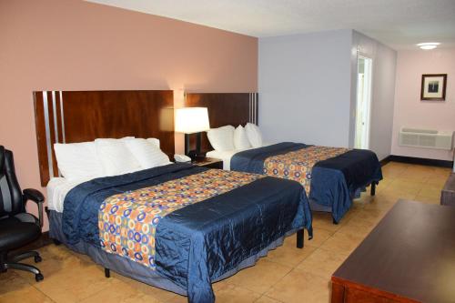 a hotel room with two beds and a table at Flamingo Motel in Okeechobee