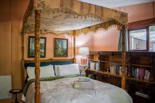 a bedroom with a canopy bed and a book shelf at Nature's Valley Health Retreat A Hide away in the Forest in Natureʼs Valley