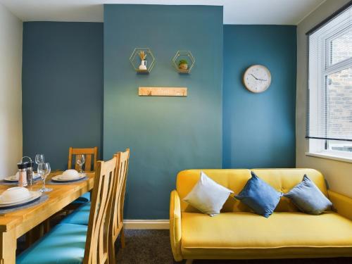 a dining room with a yellow couch and a table at Stoke On Trent - City Centre, Ideal for contractors, families, and business travelers By Doko Homes in Stoke on Trent