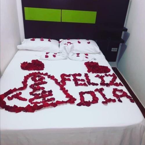 a bed with red roses on a white sheet at Estacion plaza in Ibagué