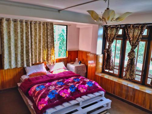 a bedroom with a large bed with purple blankets and windows at Mountain Hideaway in Darjeeling