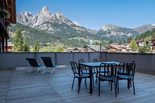 a table and chairs on a balcony with mountains at Buffaure a parte in Pozza di Fassa