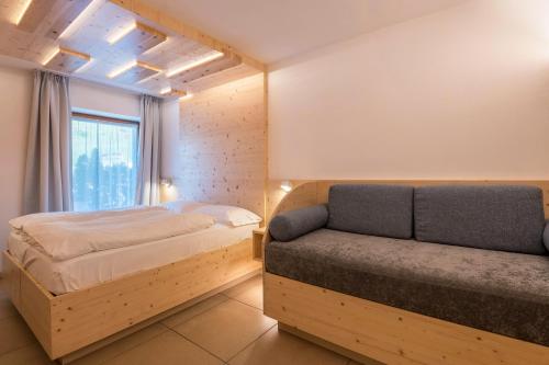 um quarto com uma cama e um sofá em Buffaure a parte em Pozza di Fassa