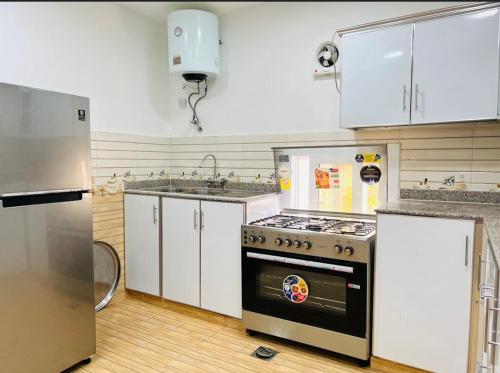 a kitchen with white cabinets and a stove top oven at Jabal Al Mumsi Chalet in Rasīs