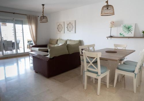 een woonkamer met een tafel en een bank bij Gran terraza, al lado del mar. in Fuengirola