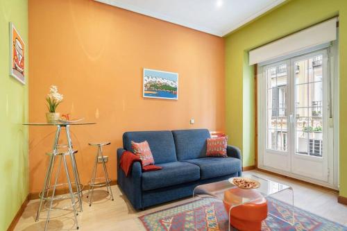 uma sala de estar com um sofá azul e uma parede laranja em Victor Apartments Chueca II em Madri