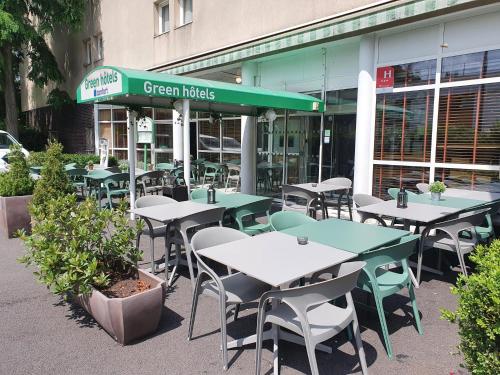 a group of tables and chairs in front of a building at Greenhotels Roissy Parc des Expositions in Tremblay En France