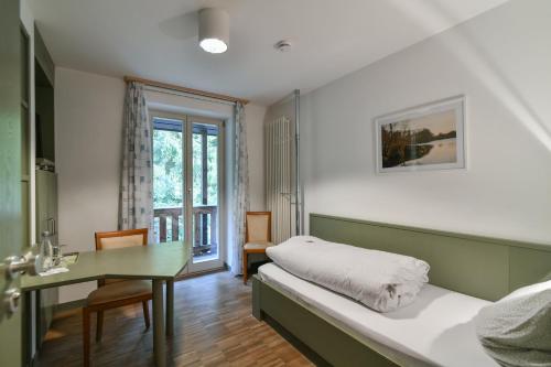 Schlafzimmer mit einem Bett, einem Schreibtisch und einem Tisch in der Unterkunft Luisenburg Resort in Wunsiedel
