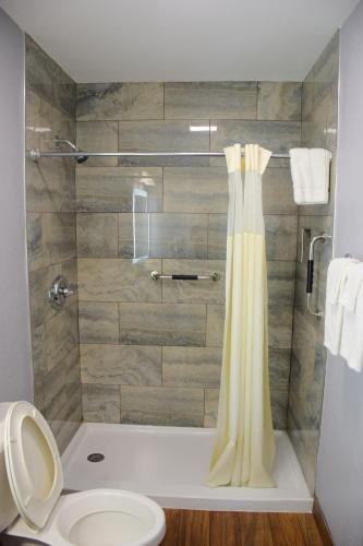 a bathroom with a shower with a yellow shower curtain at Flamingo Motel in Okeechobee