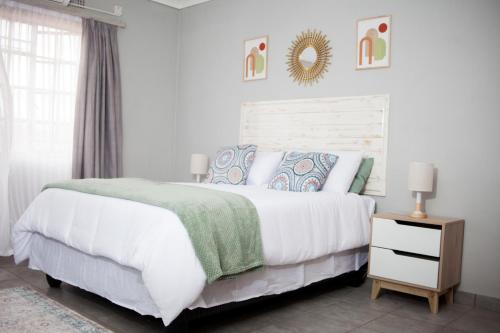 a white bedroom with a large bed and a mirror at The Cosy Crib in Palatswe