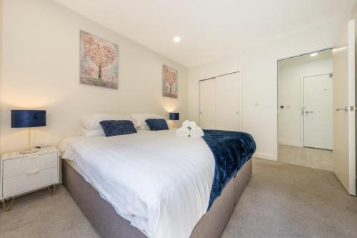 a bedroom with a large white bed with two stuffed animals on it at Modern 1 Bedroom Apartment in the center of Bedford in Bedford