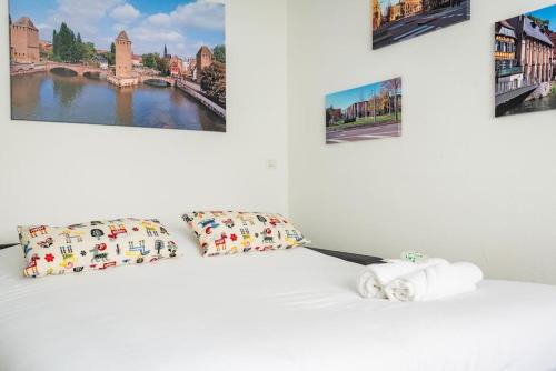 - une chambre dotée d'un lit blanc avec des oreillers et des peintures dans l'établissement Le Saint-Florent - Proche centre, CHU, Zenith et Gare, à Strasbourg