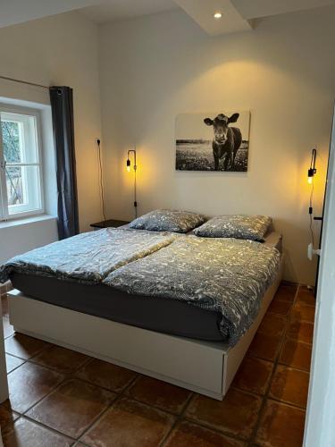 1 dormitorio con 1 cama con una foto de una vaca en la pared en Ferienwohnung Gartenglück, en Traunstein