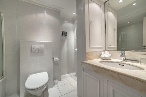 a bathroom with a toilet and a sink and a shower at Hôtel Victoria in Cannes