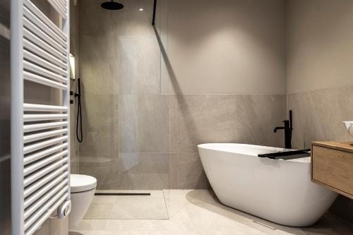 a bathroom with a white tub and a toilet at BizStay Harbour III Scheveningen Apartments in Scheveningen