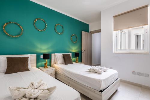 Duas camas num quarto com uma parede verde em Golden Sunsets Penthouse 10 by Solea em San Ġwann