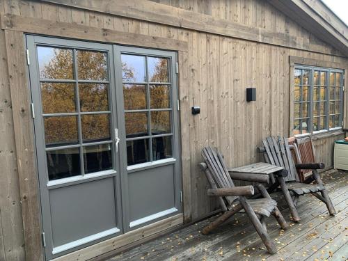eine Holzhütte mit zwei Stühlen und einer Tür in der Unterkunft New mountain lodge - Geilo-Kikut - Great location in Geilo