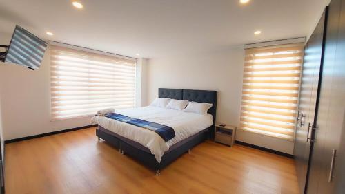 a bedroom with a large bed and two windows at La Isabella Deluxe in Mosquera