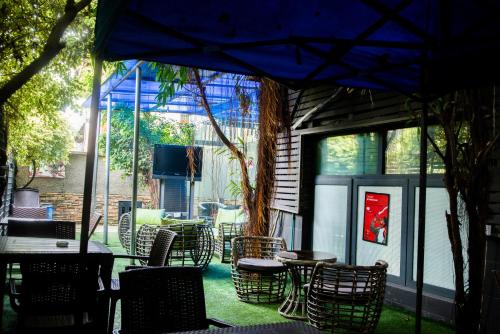 eine Terrasse mit Stühlen, Tischen und einem blauen Sonnenschirm in der Unterkunft Sese Cottage in Ikeja